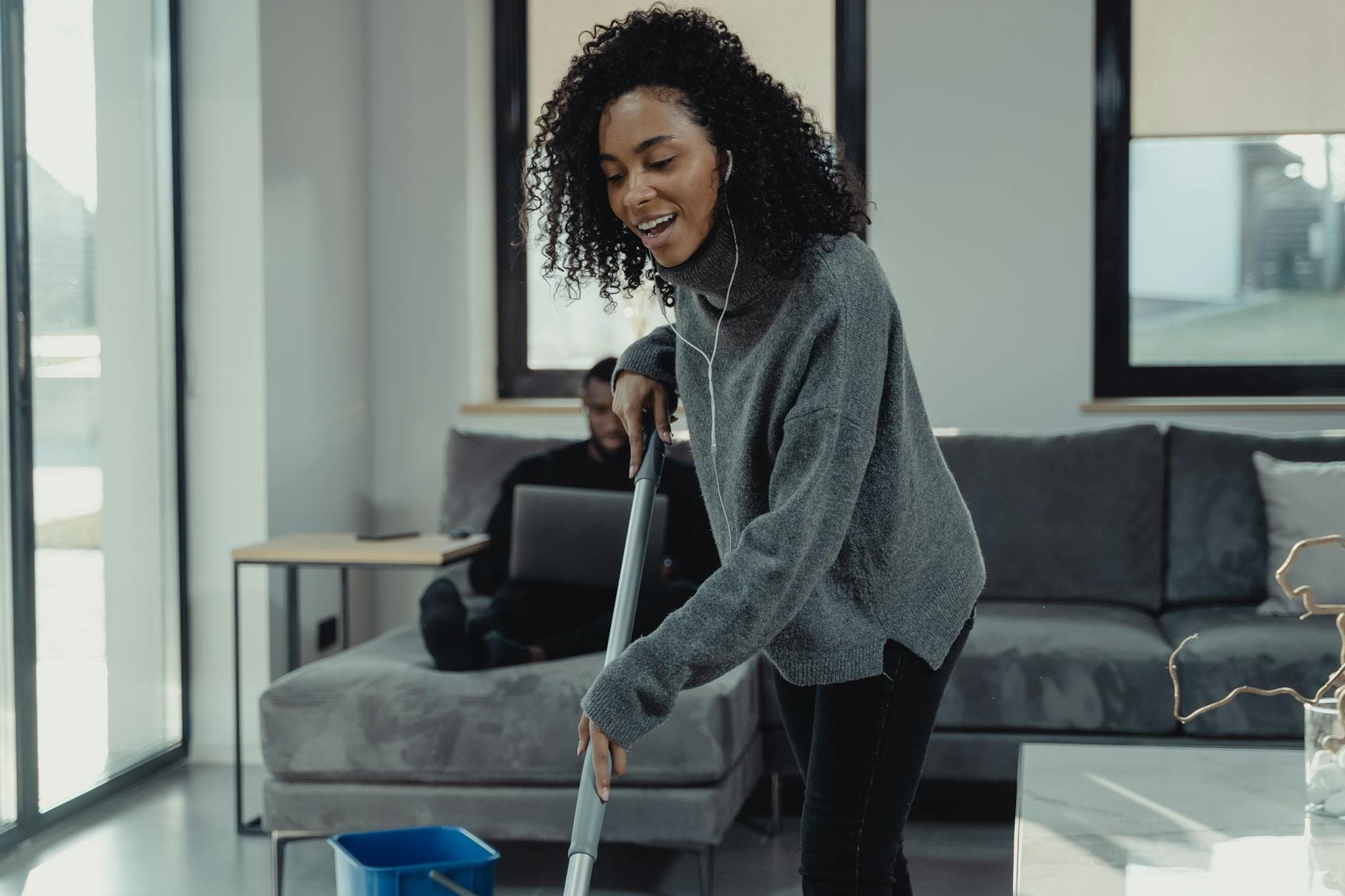 A professional house cleaner mopping the floor of a cozy Connecticut living room — How to Clean High-Rise Apartment Windows in Connecticut (Safely)