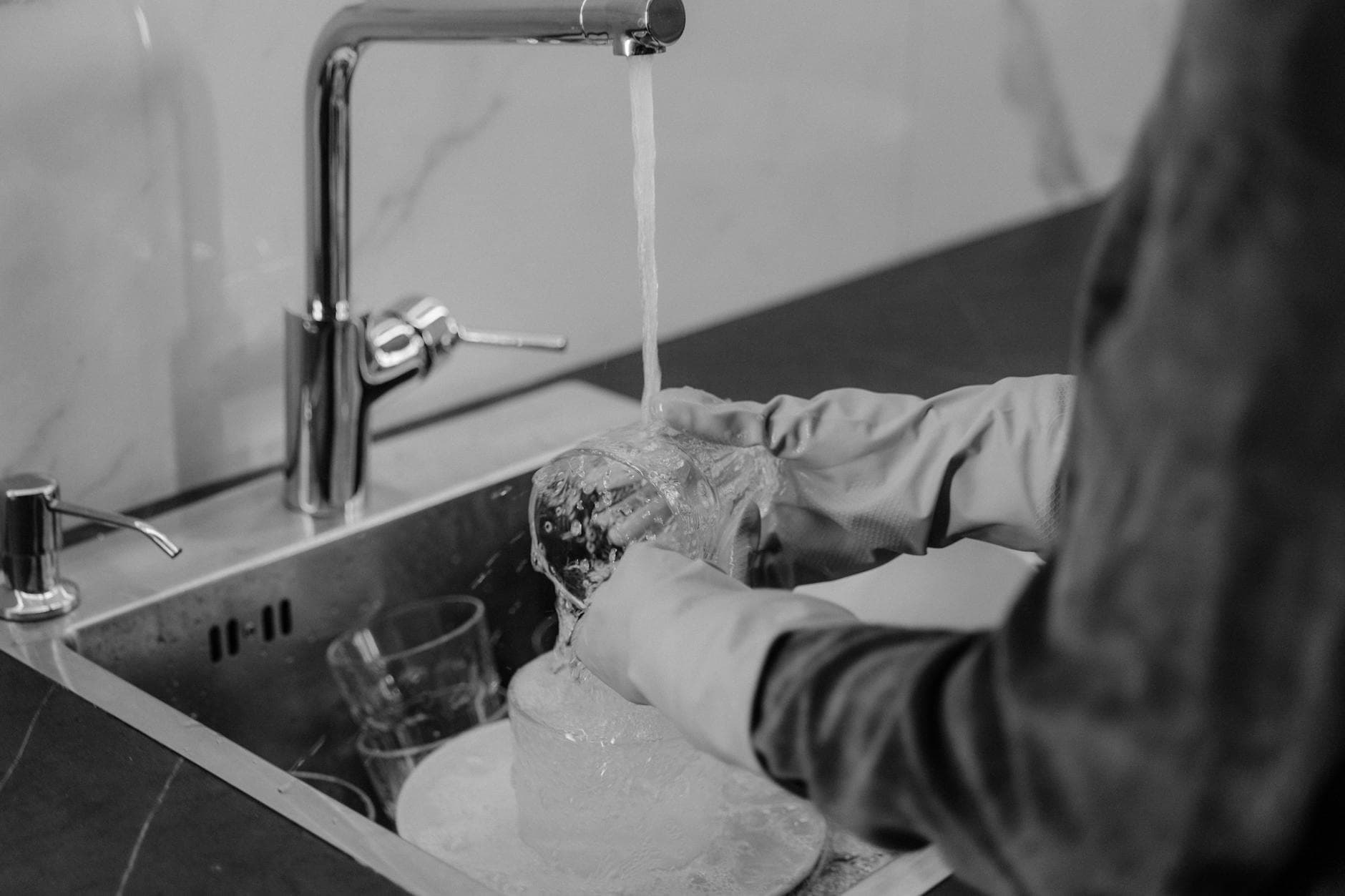Connecticut kitchen cleaning service washing dishes under running water at the sink — Deep Cleaning in Wilton, Fairfield County